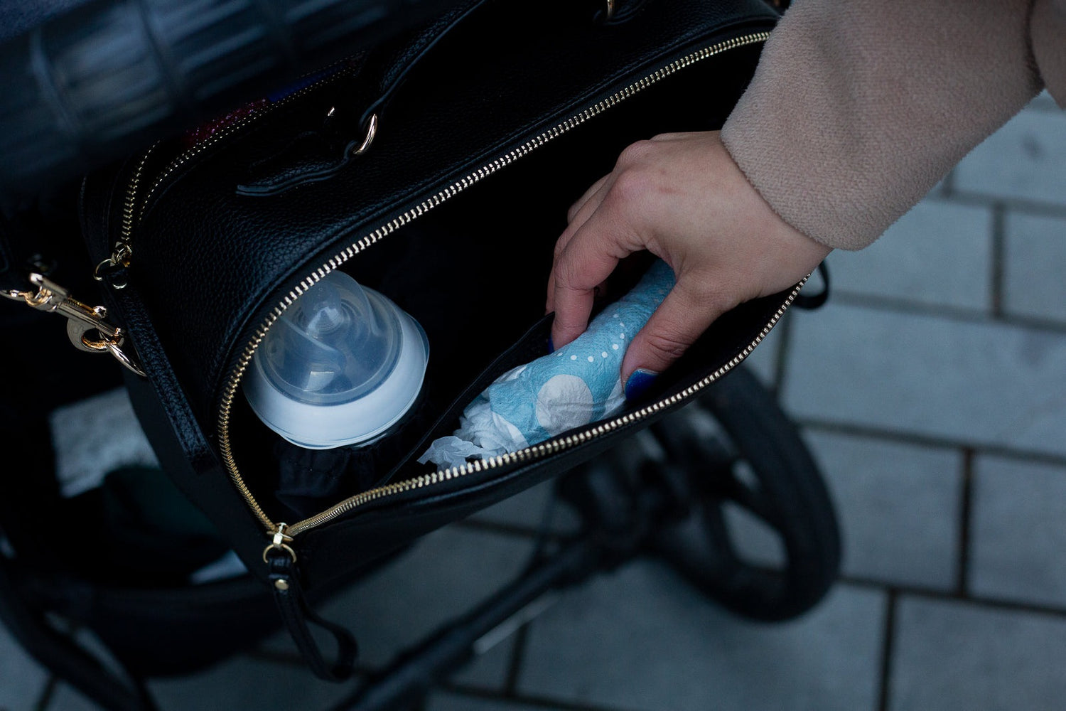 Person getting a nappy out of the pram caddy Vallarta bag. There is a insulated baby bottle holder for the tommee tippee bottles and tall milk bottles.