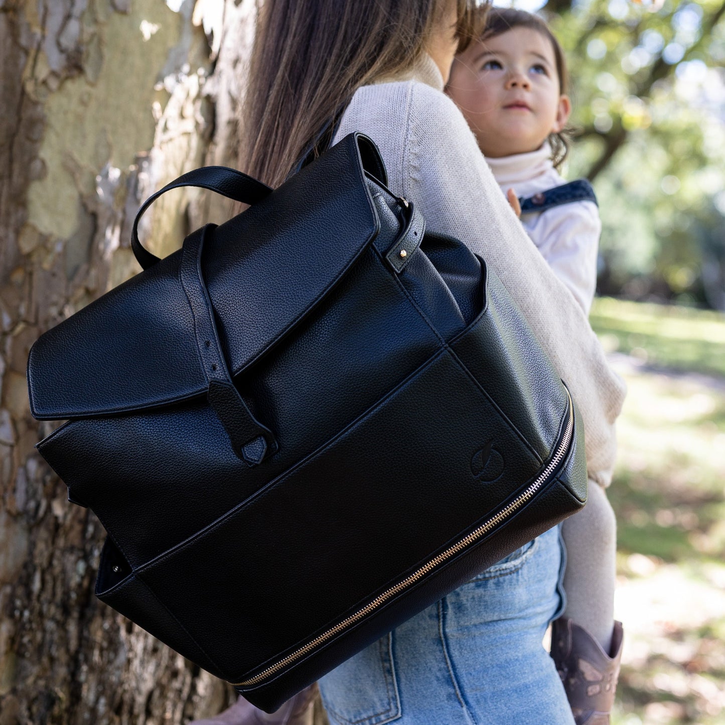 woman wearing Florence convertible totepack backpack and holding child.